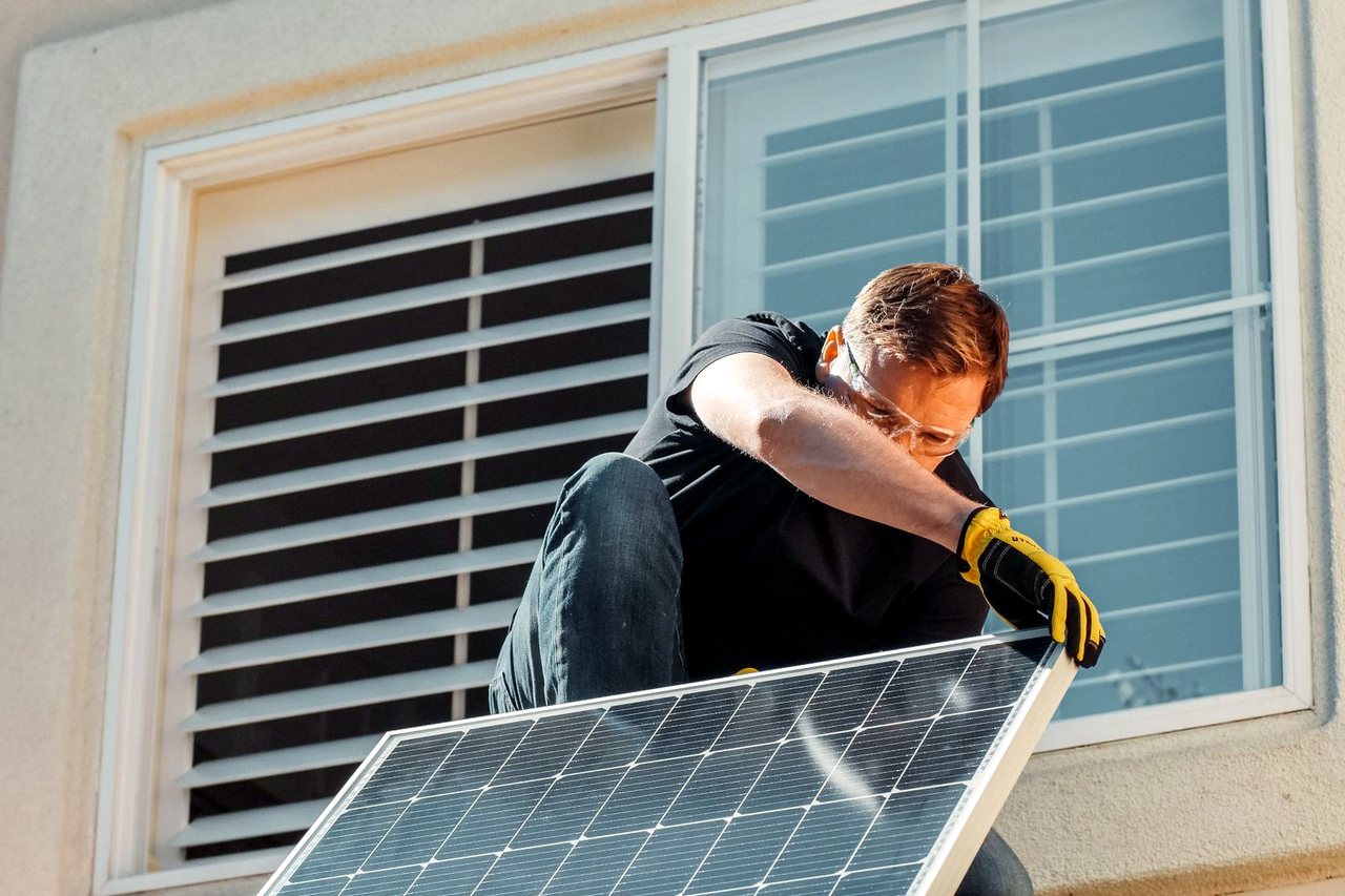 Monteur installiert ein Solarmodul an einem Wohnhaus.